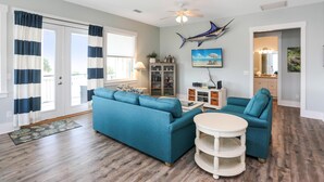 Ein Wohnzimmer mit einem blauen Modulsessel, einem weißen Couchtisch und einem Deckenventilator.