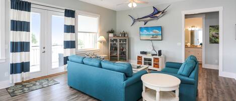 A living room with a blue sectional sofa, a white coffee table, and a ceiling fan.