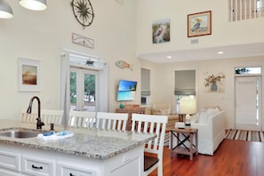 A kitchen with a granite countertop, white cabinetry, and a dining area with white chairs and a table.