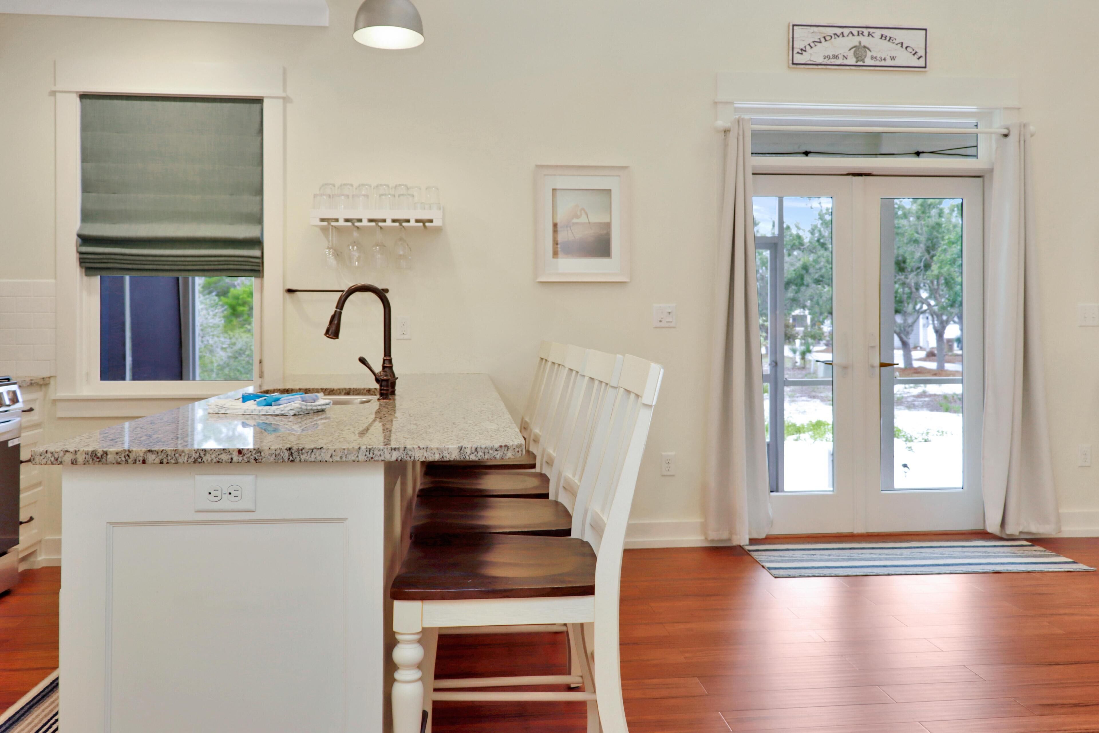 A kitchen with a wooden bench, a window with a green blind, a sink, and a door leading outside.