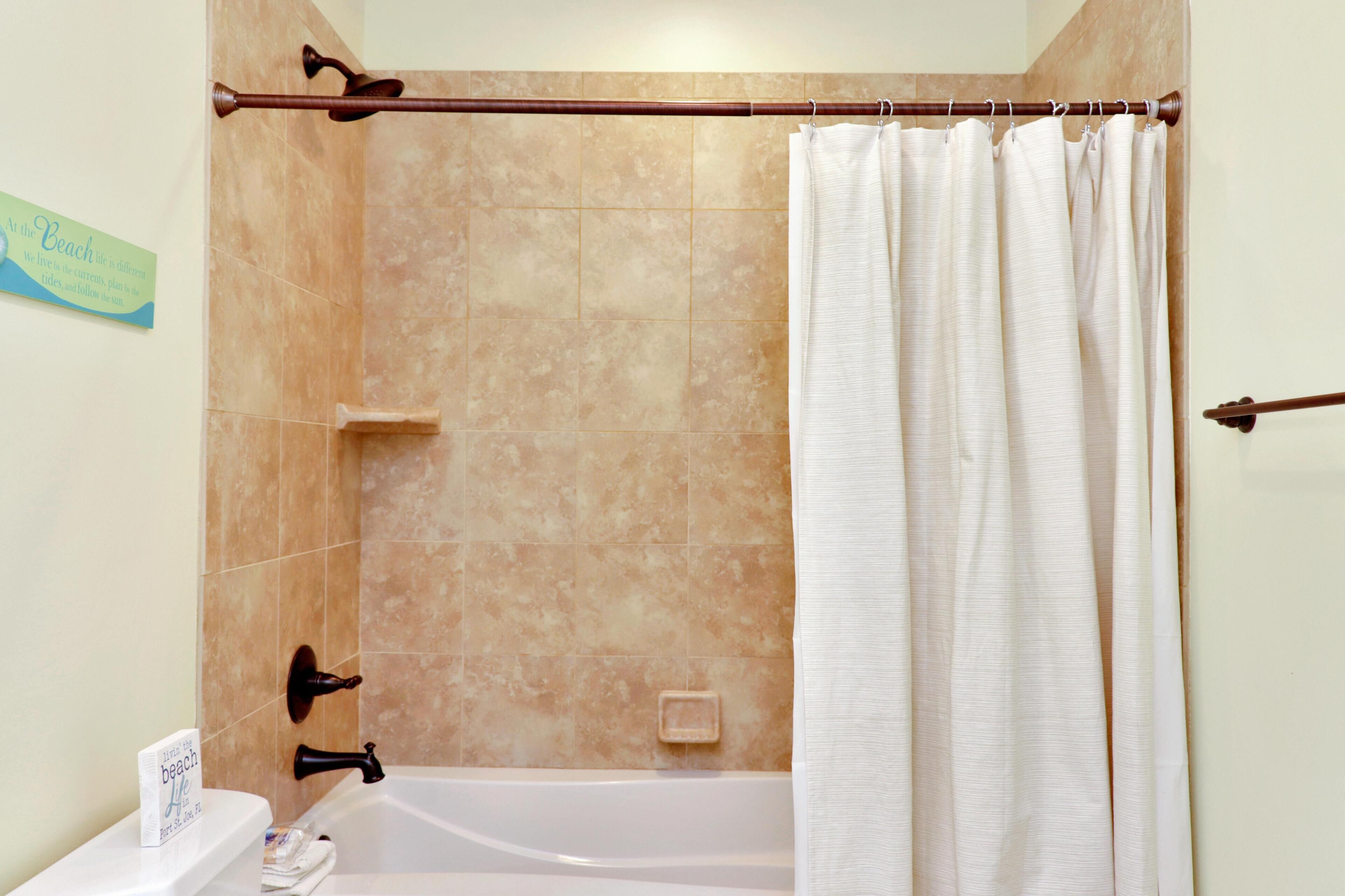 A bathroom with a bathtub, a shower curtain, and a towel rack.