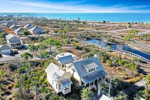 An aerial view of a coastal residential area with houses, a swimming pool, and a clear view of the ocean. - Moon & Stars (Port St. Joe)