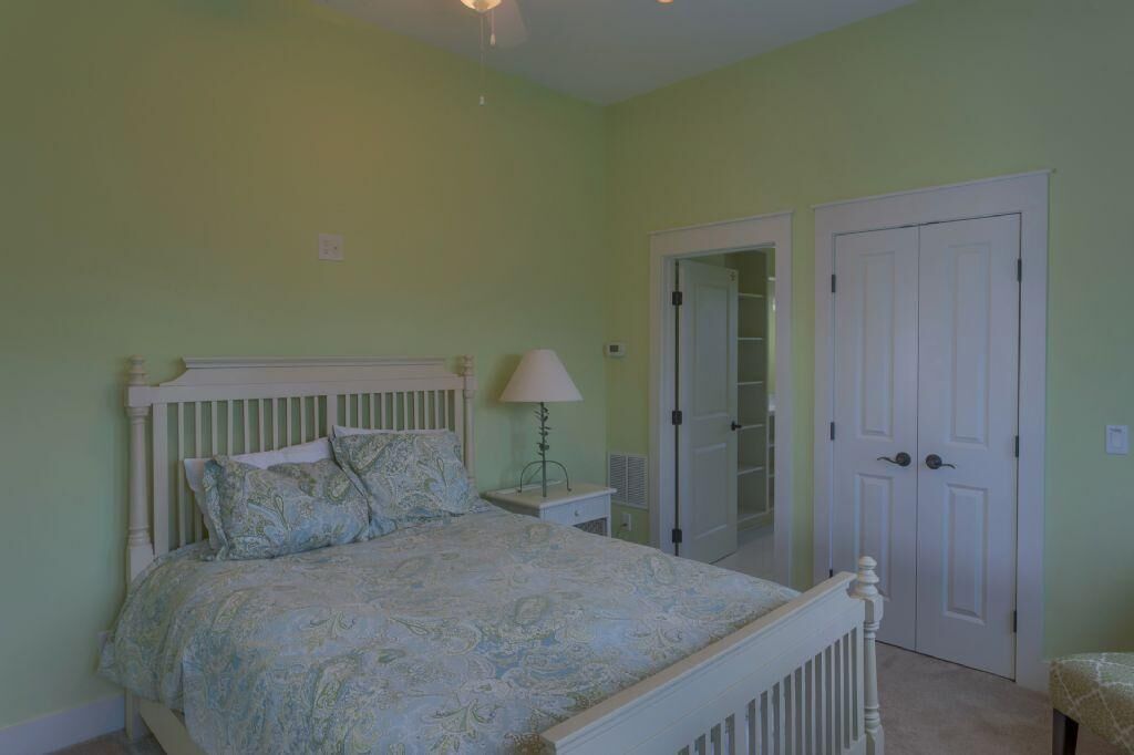 A bedroom with a bed, nightstand, lamp, and a closet with a mirror.