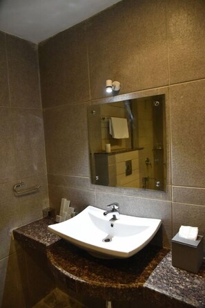 A bathroom with a white sink, a mirror, and a towel dispenser. - Rester Select Jodhpur (Jodhpur)