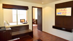 A hotel room with a bed, a desk, a TV mounted on the wall, and a window with a view of the outside. - Rester Select Jodhpur (Jodhpur)