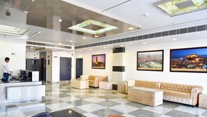 A hotel lobby with a checkered floor, a reception desk, a sofa, and two framed pictures on the wall. - Rester Select Jodhpur (Jodhpur)