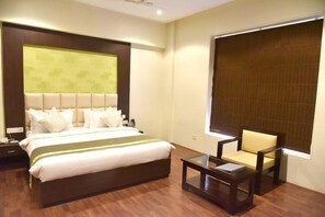 A hotel room with a large bed, a small table, a chair, and a window with blinds. - Rester Select Jodhpur (Jodhpur)