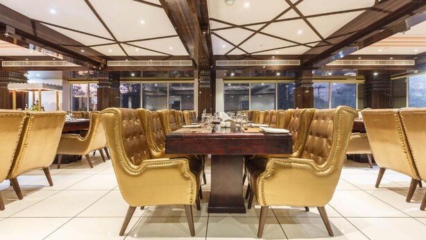 A spacious dining area with a large central table surrounded by high-backed chairs. - Rester Select Jodhpur (Jodhpur)