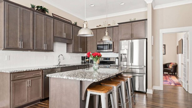 A modern kitchen with dark wood cabinets, stainless steel appliances, and a granite countertop.