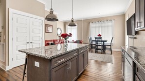 A modern kitchen with a granite countertop, dark cabinetry, and pendant lighting.