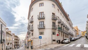 En byggnad med flera våningar, balkonger, ett övergångsställe och parkerade bilar längs gatan.