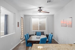 A dining area with a table, chairs, a ceiling fan, and a window with blinds. - Entire home in beautiful Southwest Las Vegas, NV area! (Las Vegas)