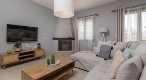 A modern living room with a flat-screen TV, a fireplace, a sofa, and a coffee table.