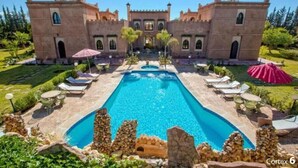 A pool surrounded by stone walls and two large buildings with arched windows. - Palace With 2 Villas and 2 Swimming Pools in Sidi Abdellah Ghiat (Sidi Abdallah Ghiat)