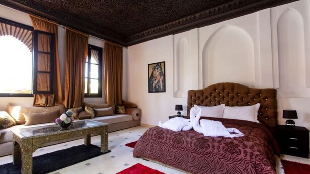 A hotel room with a large bed, a sofa, a coffee table, and a painting on the wall. - Palace With 2 Villas and 2 Swimming Pools in Sidi Abdellah Ghiat (Sidi Abdallah Ghiat)