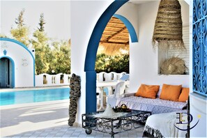 A poolside area with a white pool, blue and white furniture, and a wicker hanging lamp. - Villa Azalée Eden Luxe (Aghir)