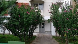 A multi-story building with a central entrance, surrounded by greenery and flowering bushes. - Near Lake, With View, Center (Ohrid)
