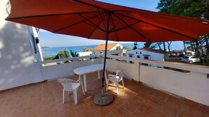 A balcony with a red umbrella, white chairs, and a round table. - Apartment 2 Near the sea (Preko)