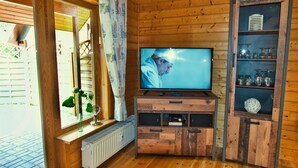 A wooden interior with a television on a wooden stand, a radiator, and a glass cabinet with shelves. - The House to Stay for Holidays (Oberharz am Brocken)