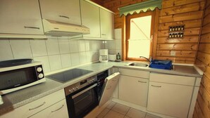 A compact kitchen with white cabinets, a microwave, an oven, and a sink. - The House to Stay for Holidays (Oberharz am Brocken)