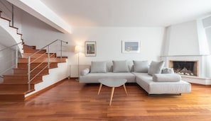 A modern living room with a staircase, a sofa set, a coffee table, and a fireplace. - Adelos III Bloom Villa 5BR 360m² - Sauna - Rooftop (Elliniko-Argyroupoli)