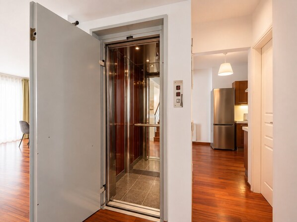 A modern kitchen with a stainless steel refrigerator, wooden cabinets, and a pendant light.