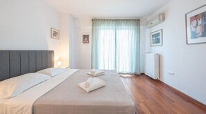 Hotellihuone, jossa on sänky, patteri ja ikkuna, jossa on verhot.