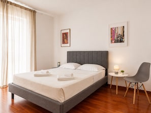 A modern hotel room with a bed, a chair, a small table, and two framed pictures on the wall. - Adelos III Bloom Villa 5BR 360m² - Sauna - Rooftop (Elliniko-Argyroupoli)