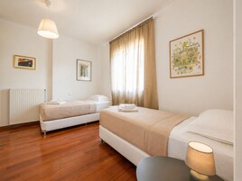 Una habitación de hotel con dos camas, un radiador, una lámpara y dos cuadros en la pared.