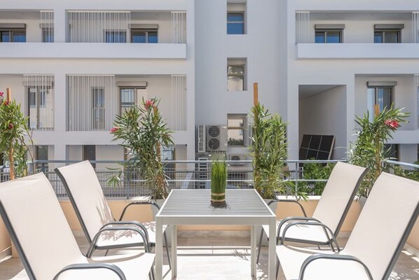 A balcony with a table and chairs, surrounded by potted plants.