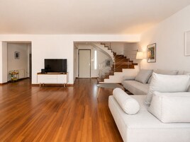Una sala de estar moderna con un televisor de pantalla plana, un sofá, una mesa de centro y una escalera.