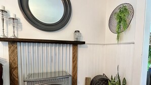A modern living room with a wood-burning stove, a mirror, and a potted plant. - 100 year old Farm Cottage. Minutes from the beach! (Nanaimo)