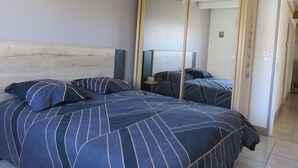 Un dormitorio con cama, espejo y mesita de noche.