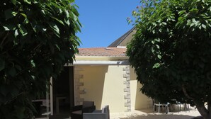 Un patio con mobiliario exterior, techo de baldosas y pared de piedra.