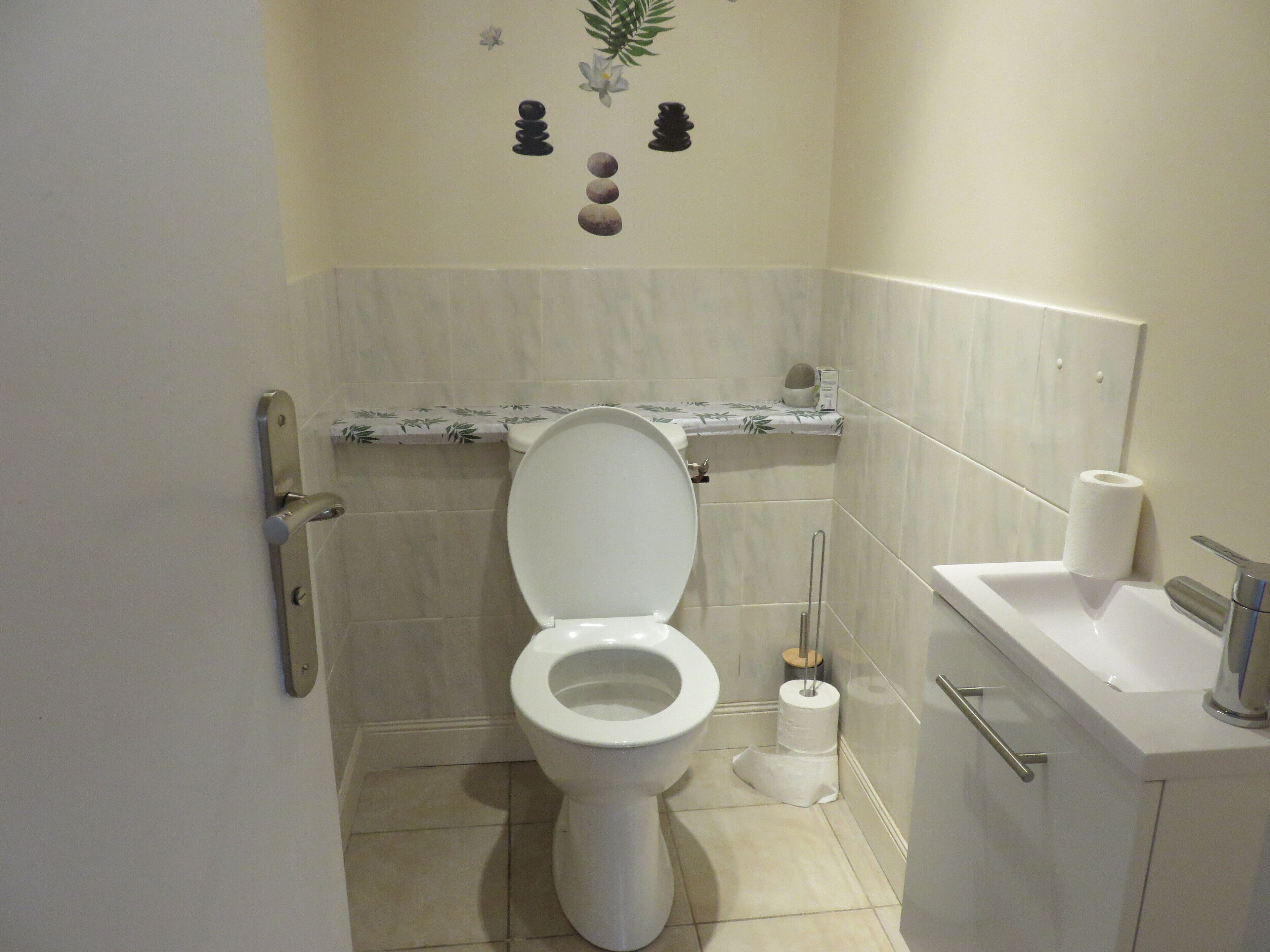 Une salle de bain équipée de toilettes, d’un lavabo et d’un porte-rouleau de papier toilette.