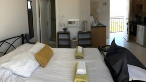 Ett hotellrum med en säng, ett skrivbord, ett litet pentry och ett badrum.