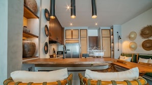 A modern kitchen with a central island, wooden chairs, and a dining table. - Apartment Seabreeze 1 (Canggu)