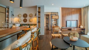 A modern living room with a wooden dining table, chairs, a TV, and a bookshelf. - Apartment Seabreeze 1 (Canggu)