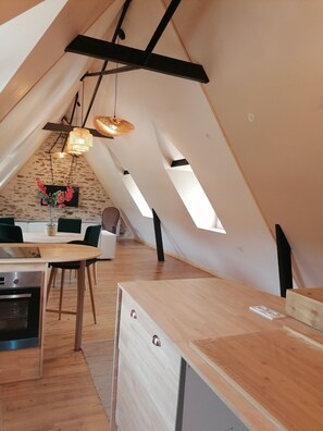 Ein modernes, gemütliches Interieur mit einem Holzespeisetisch, einer Küchenzeile und einer Sitzecke mit Sofa und Sesseln.