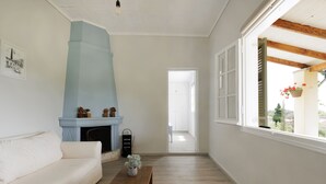A living room with a white sofa, a wooden coffee table, a blue fireplace, and a view through a window.