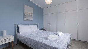 A bedroom with a bed, bedside table, wardrobe, and a hanging light fixture.