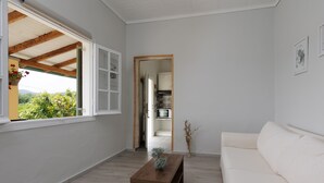 A spacious living area with a white sofa, a wooden coffee table, and a view of a kitchen through an open doorway.
