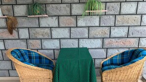 Un conjunto de silla y mesa de mimbre frente a una pared de piedra con plantas en macetas.