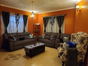 A living room with two sofas, a coffee table, and a floral armchair. - A quiet and a secured place next to JKIA airport (Nairobi)