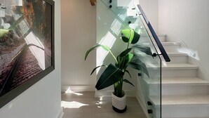 A modern staircase with glass railings, a potted plant, and a framed picture on the wall. - Muskoka Lakefront Resort - 5 Bedroom Modern Cottage (Muskoka Lakes)