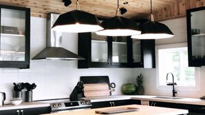 A modern kitchen with a central island, black cabinetry, and pendant lighting. - Muskoka Lakefront Resort - 5 Bedroom Modern Cottage (Muskoka Lakes)