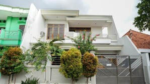 Una casa moderna de dos pisos con fachada blanca, balcón y entrada protegida por una reja.