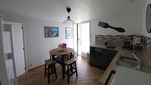 Una cucina con zona pranzo, pavimento in legno, lampadario a sospensione e un grande orologio a parete.