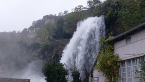 Una cascata che si getta da una scogliera rocciosa, circondata da una vegetazione lussureggiante.