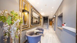 A modern hotel hallway with a staircase, a large mirror, and two seating areas. - King Suits Hotel (Istanbul)